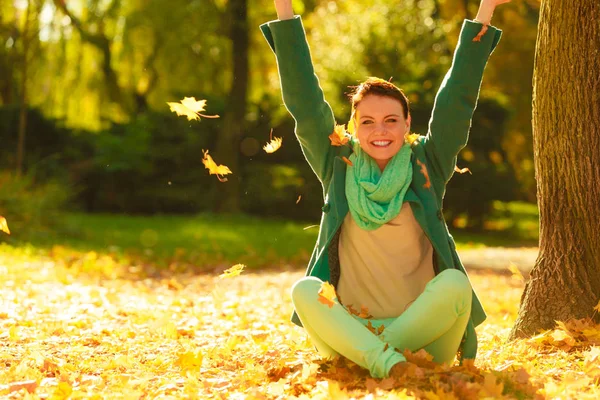 Lycklig kvinna kastar hösten lämnar i park — Stockfoto