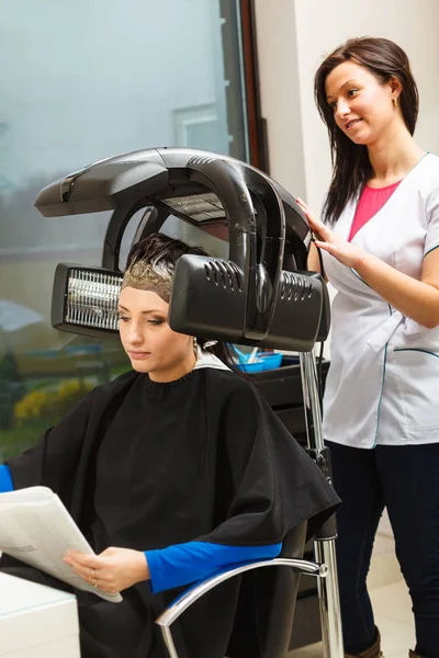 Donna in parrucchiere, asciugatura capelli sotto macchina — Foto Stock