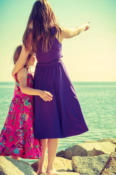 Mother daughter at rocks pointing at sea — Stock Photo, Image