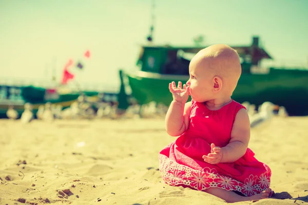 Pequeno bebê sentado tentando comer areia — Fotografia de Stock