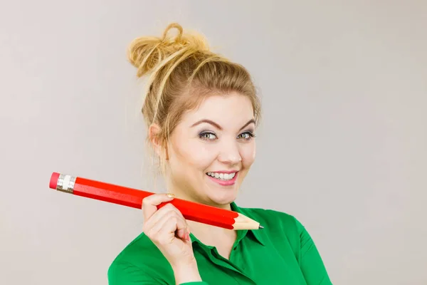 Lachende vrouw houdt grote potlood in de hand — Stockfoto