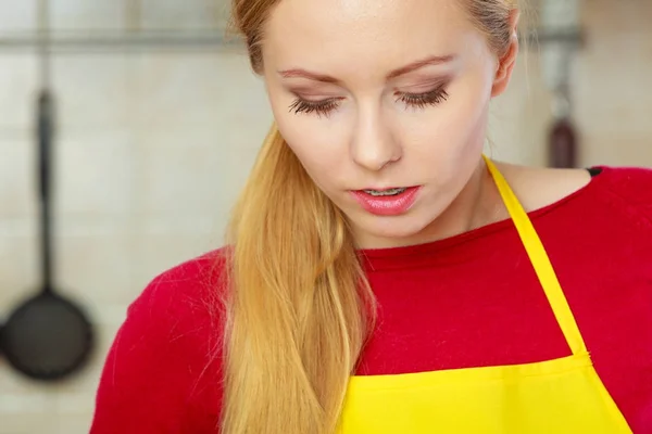 Blonde woman in kitchen wearing apron — Stock Photo, Image