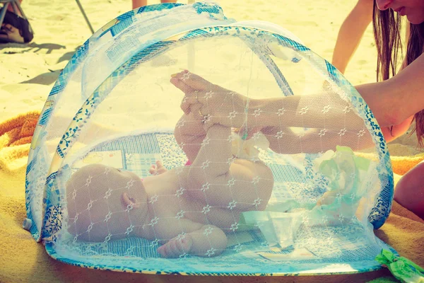 Mujer swaddle bebé en la playa — Foto de Stock
