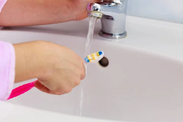 Mão segurando escova de dentes no banheiro — Fotografia de Stock