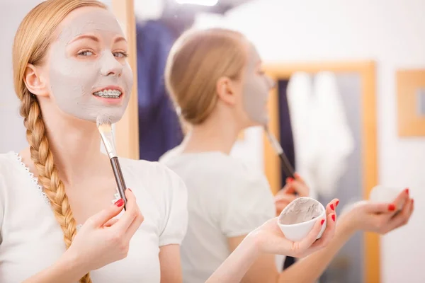 Vrouw met borstel klei modder masker toepassen op haar gezicht — Stockfoto