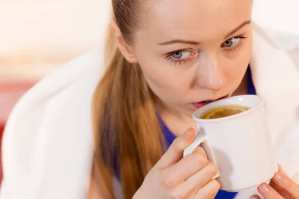 Donna sdraiata sul divano sotto coperta a bere tè — Foto Stock