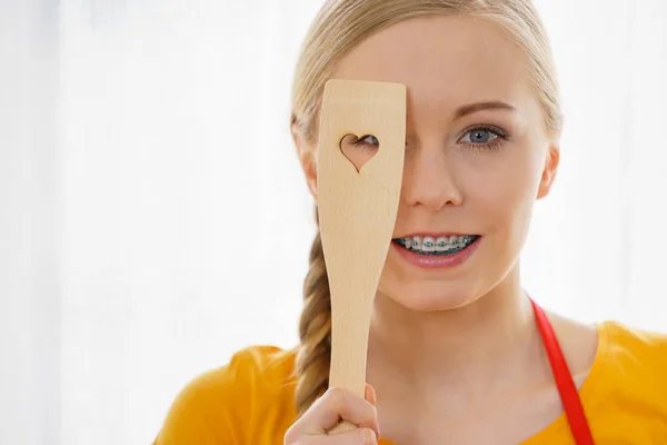 Woman holding wooden spatula with heart — Stock Photo, Image