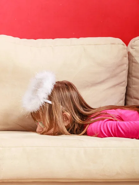 Bored girl dressed as an angel lying on sofa — Stock Photo, Image