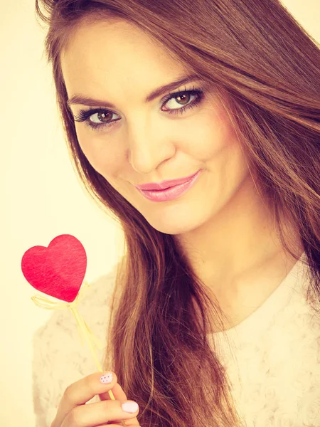 Flirty woman holding red wooden heart on stick — Stock Photo, Image