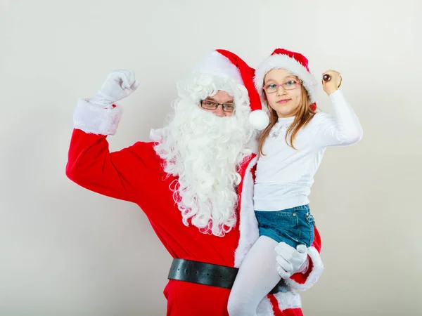 Christmas Santa Claus holding girl in christmassy hat — Stock Photo, Image