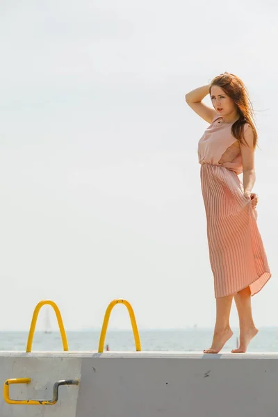 Vrouw lang licht roze jurk dragen op steiger — Stockfoto