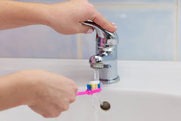 Рука тримає зубну щітку у ванній — стокове фото