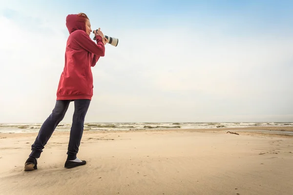 Žena kráčející po pláži s kamerou — Stock fotografie