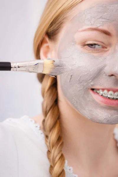 Frau trägt mit Pinsel Lehmmaske auf ihr Gesicht auf — Stockfoto