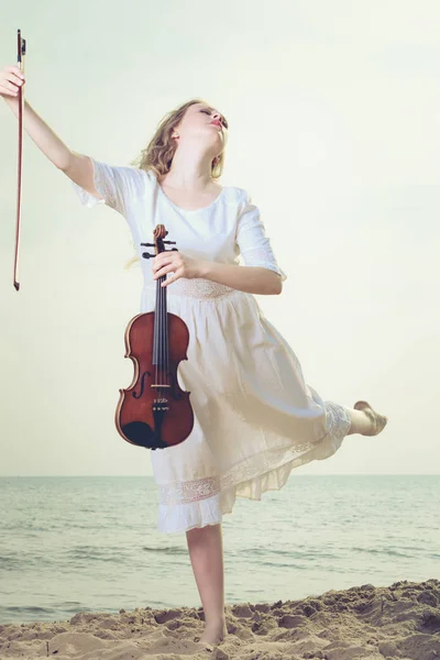 Жінка на пляжі біля моря тримає скрипку — стокове фото