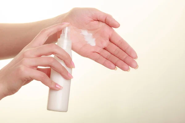 Mujer poniendo crema blanca en la mano — Foto de Stock