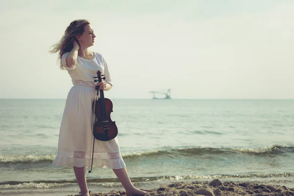 Woman on beach near sea holding violin — Stock Photo, Image