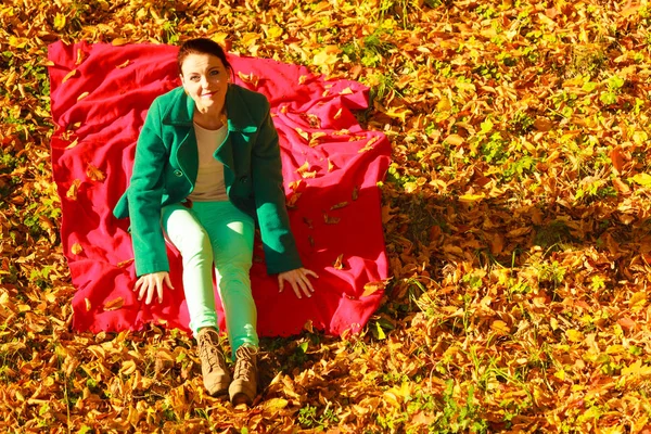 Женщина сидит на осенних листьях — стоковое фото