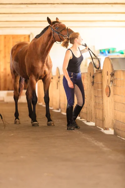 Jokey genç kız kahverengi atı okşuyor. — Stok fotoğraf
