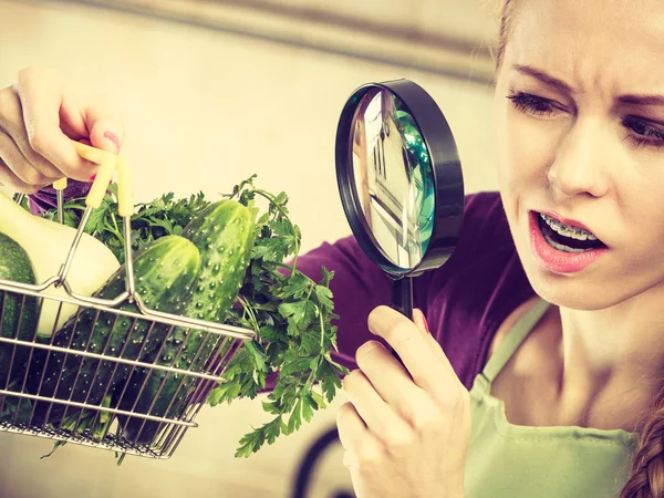 Жінка дивиться через збільшувач в кошику з овочами — стокове фото
