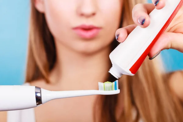 Woman applying toothpaste on her toothbrush — Stock Photo, Image