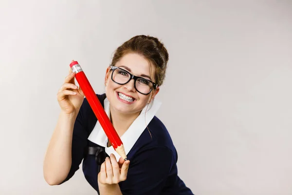 Mujer sonriente sostiene un lápiz grande en la mano — Foto de Stock