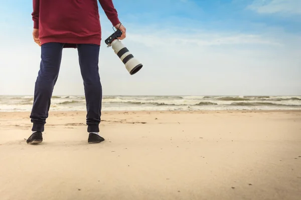 Vrouw lopend op het strand met camera — Stockfoto