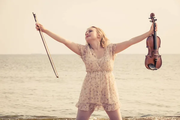 Woman on beach near sea holding violin — Stock Photo, Image