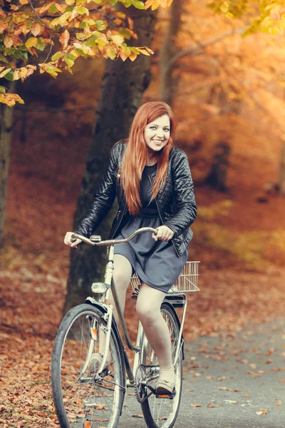 Menina de cabelos vermelhos andando de bicicleta no parque outonal — Fotografia de Stock