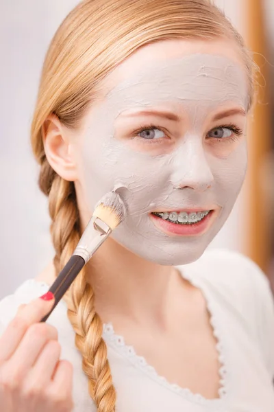 Vrouw met borstel klei modder masker toepassen op haar gezicht — Stockfoto