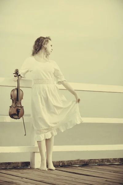 Woman on pier outside holding violin — Stock Photo, Image