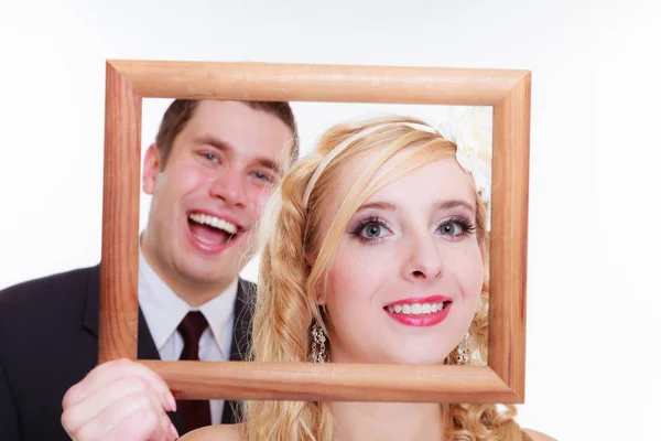 Groom and bride holding empty frame — Stock Photo, Image