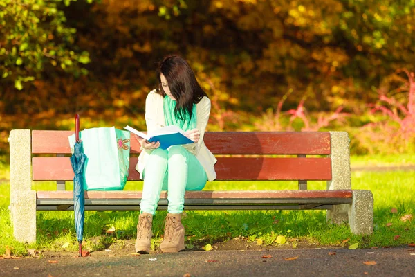 Frau liest Buch auf Bank im Park — Stockfoto