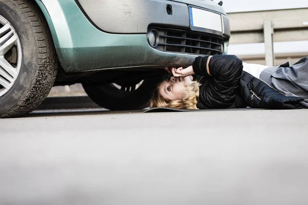Kobieta, Naprawianie uszkodzonego samochodu leżącego pod nim — Zdjęcie stockowe