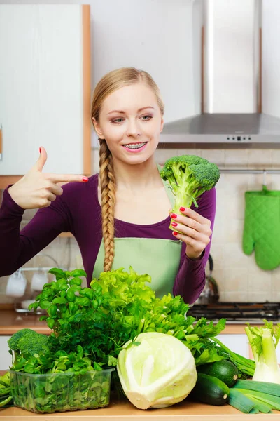 Жінка на кухні з зеленими овочами брокколі в руці — стокове фото