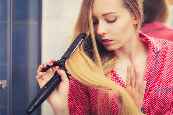 Mulher endireitando seu longo cabelo loiro — Fotografia de Stock
