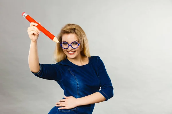 Mujer sonriente sostiene un lápiz grande en la mano — Foto de Stock