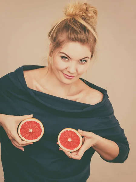 Woman holding red grapefruit on breast — Stock Photo, Image