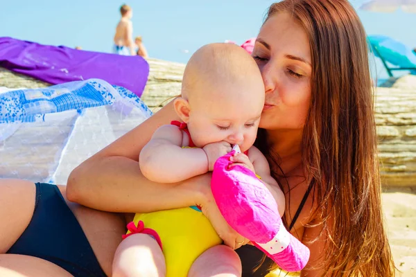 Madre baciare bambino in costume da bagno sulla spiaggia — Foto Stock