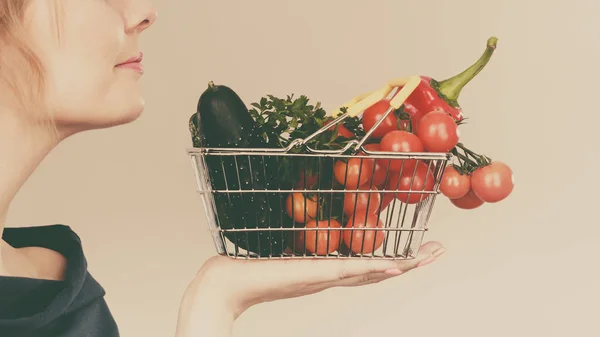 Mujer sostiene cesta de la compra con verduras, oliendo —  Fotos de Stock