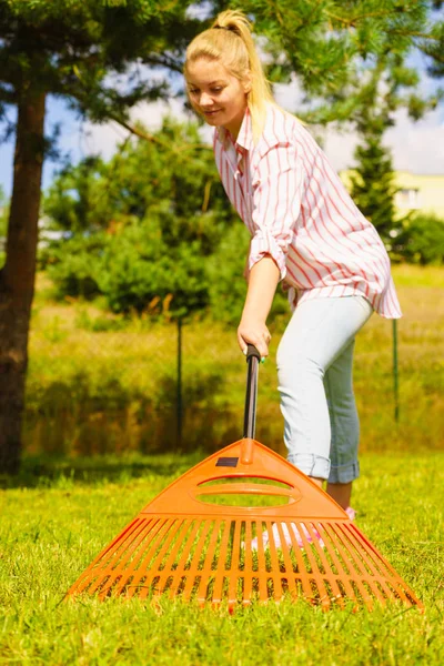 Donna che usa rastrello per pulire il giardino — Foto Stock