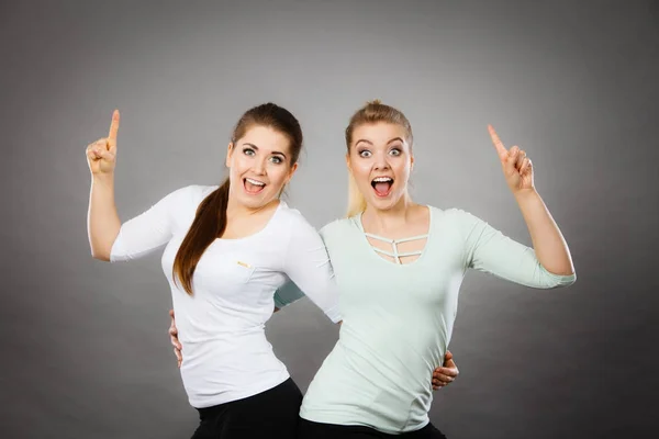 Glückliche Frauen, die mit einem Finger nach oben zeigen. — Stockfoto