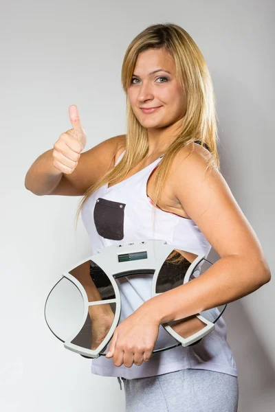 Счастливая женщина, держащая машину веса, показывая большой палец вверх — стоковое фото