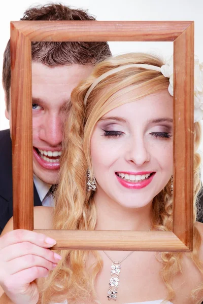 Brudgummen och bruden håller tom ram — Stockfoto