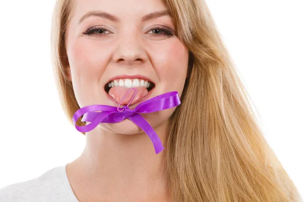 Blonde woman biting decorative purple bow — Stock Photo, Image