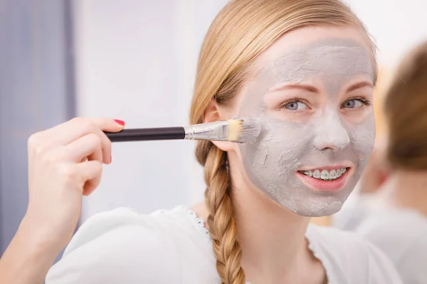 Vrouw met borstel klei modder masker toepassen op haar gezicht — Stockfoto