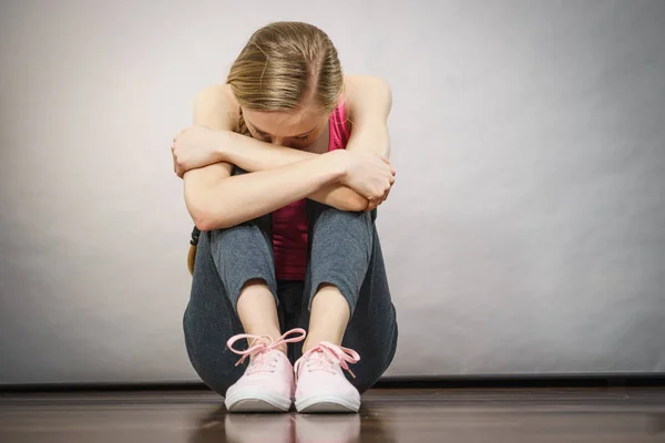 Сумна пригнічена молода дівчина-підліток сидить біля стіни — стокове фото