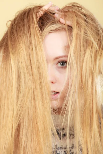 Blond kvinna som håller henne länge trassligt hår — Stockfoto
