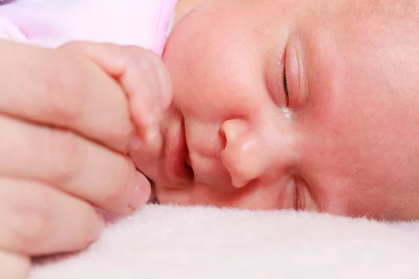 Bebé durmiendo en manta sosteniendo la mano madre —  Fotos de Stock