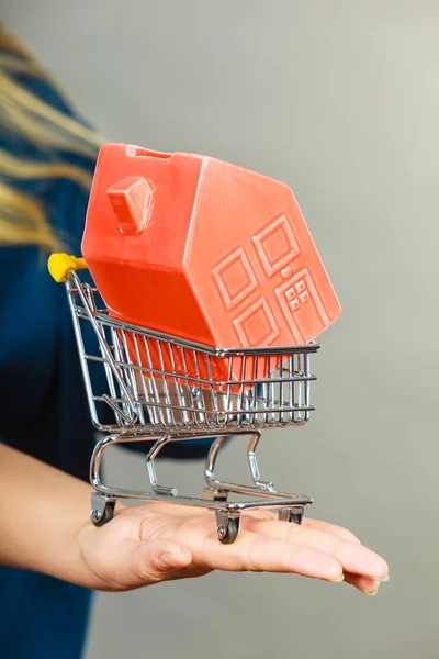 Vrouw hand hebt winkelwagentje met huis binnen — Stockfoto